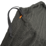 Close-up of a textured gray fabric with a black drawstring and orange tag.