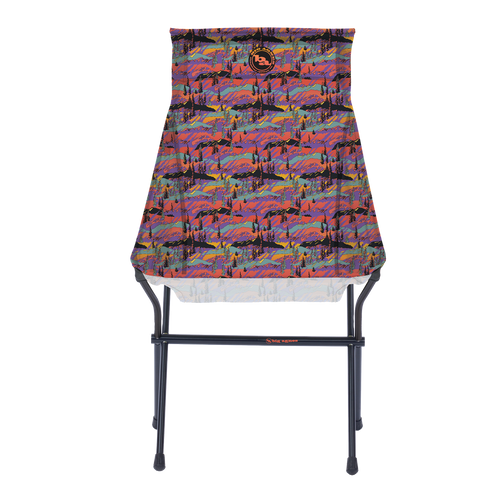 The Big Agnes Big Six Camp Chair - Alpenglow is a lightweight, packable camp chair with a black metal frame and a colorful seat featuring a vibrant abstract mountain landscape in red, purple, blue, and orange.