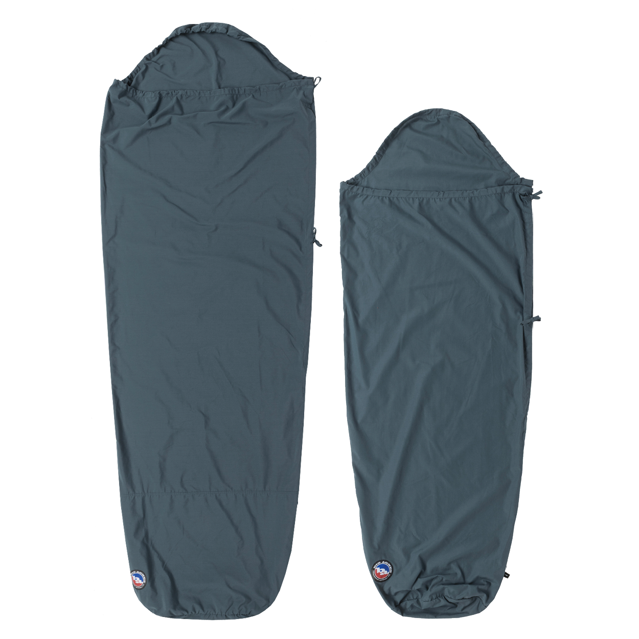 Two dark blue Big Agnes Cotton Sleeping Bag Liners are laid flat. The left is rectangular with a hood; the right is a tapered mummy style. Both feature a small logo at the bottom and are ideal for travel.