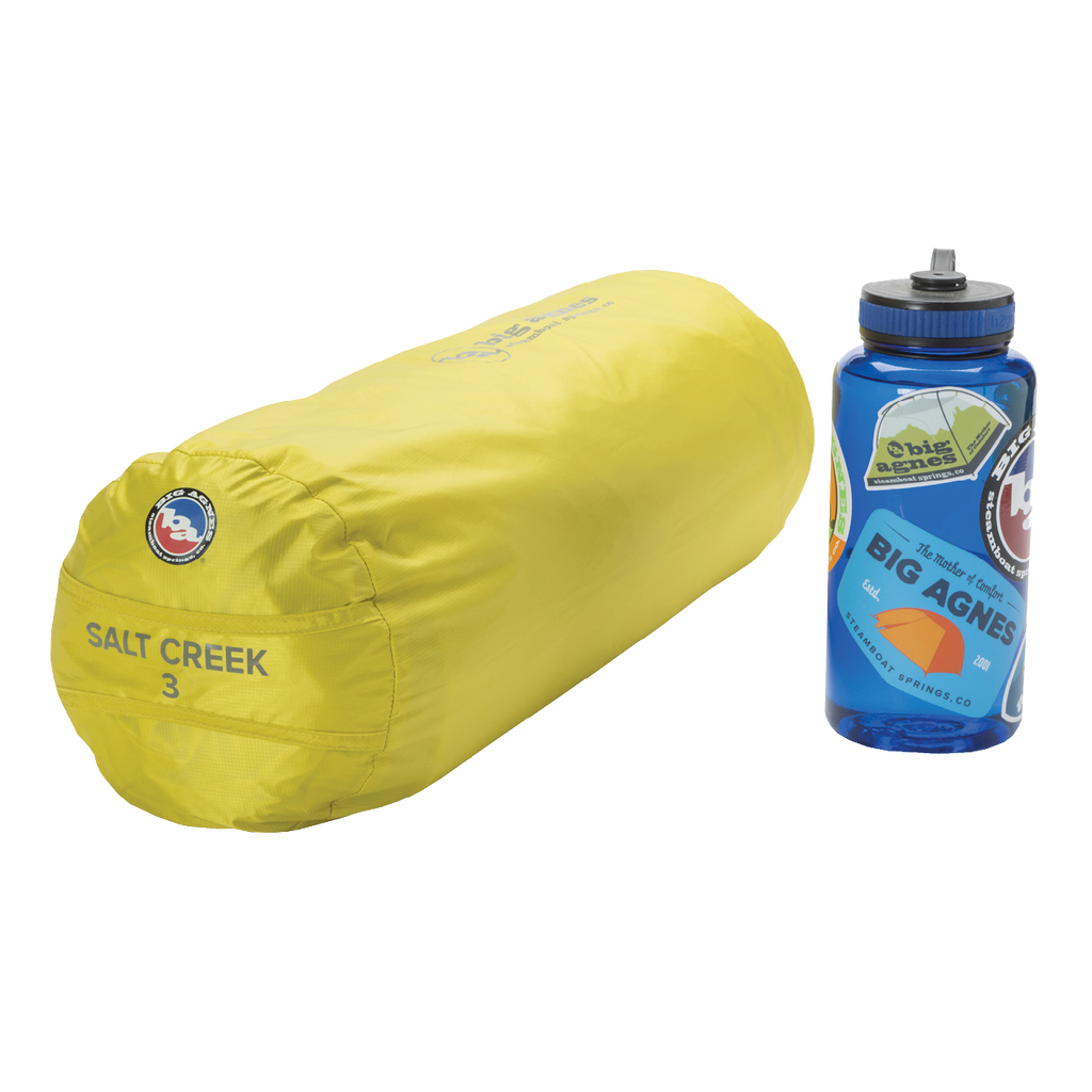 A yellow Big Agnes Salt Creek 3 tent storage bag sits beside a blue water bottle with outdoor-themed stickers on a white background.