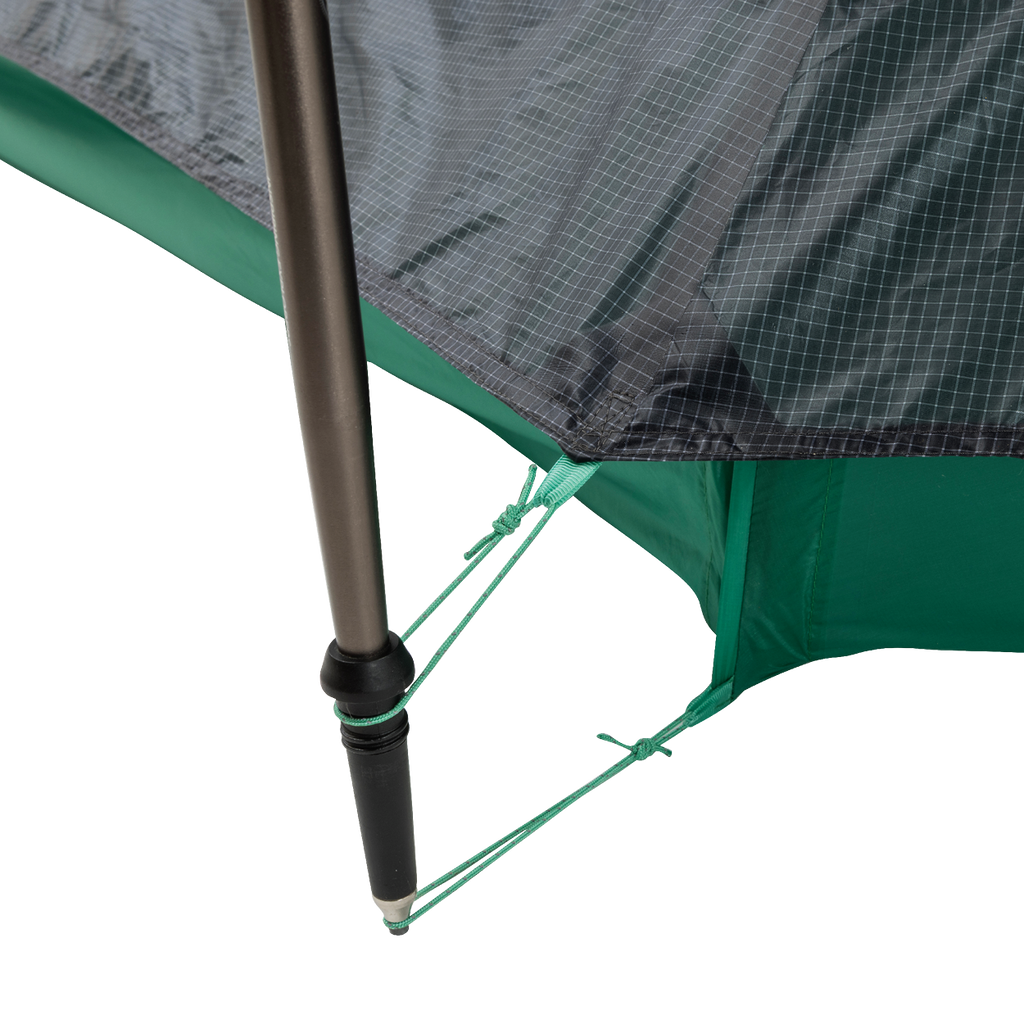 Close-up of a String Ridge VST 1.5 tent corner by Big Agnes, showing a black pole secured with green guy lines on reinforced, grid-patterned green and gray fabric—highlighting this ultralight shelter’s durability and detailed design.
