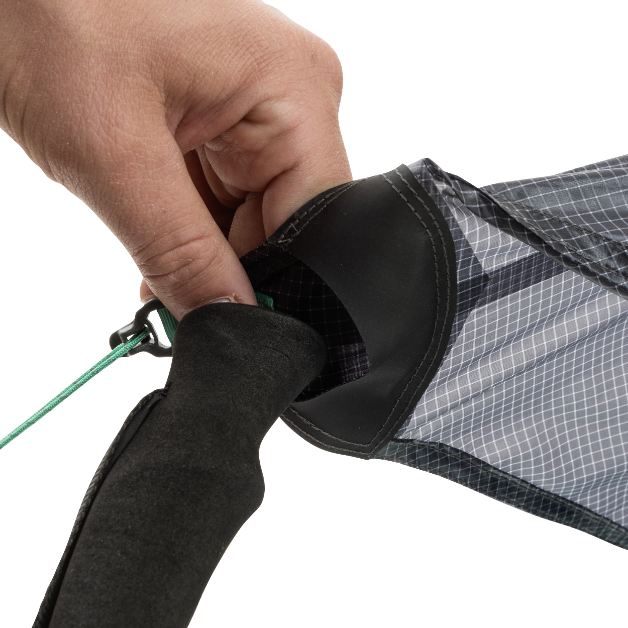 A close-up of a hand tying a green string to the end of the black and gray String Ridge VST 1.5 by Big Agnes Returns, highlighting its detailed fabric and handle—ideal for assembling ultralight shelters or VST tents on your outdoor trips.