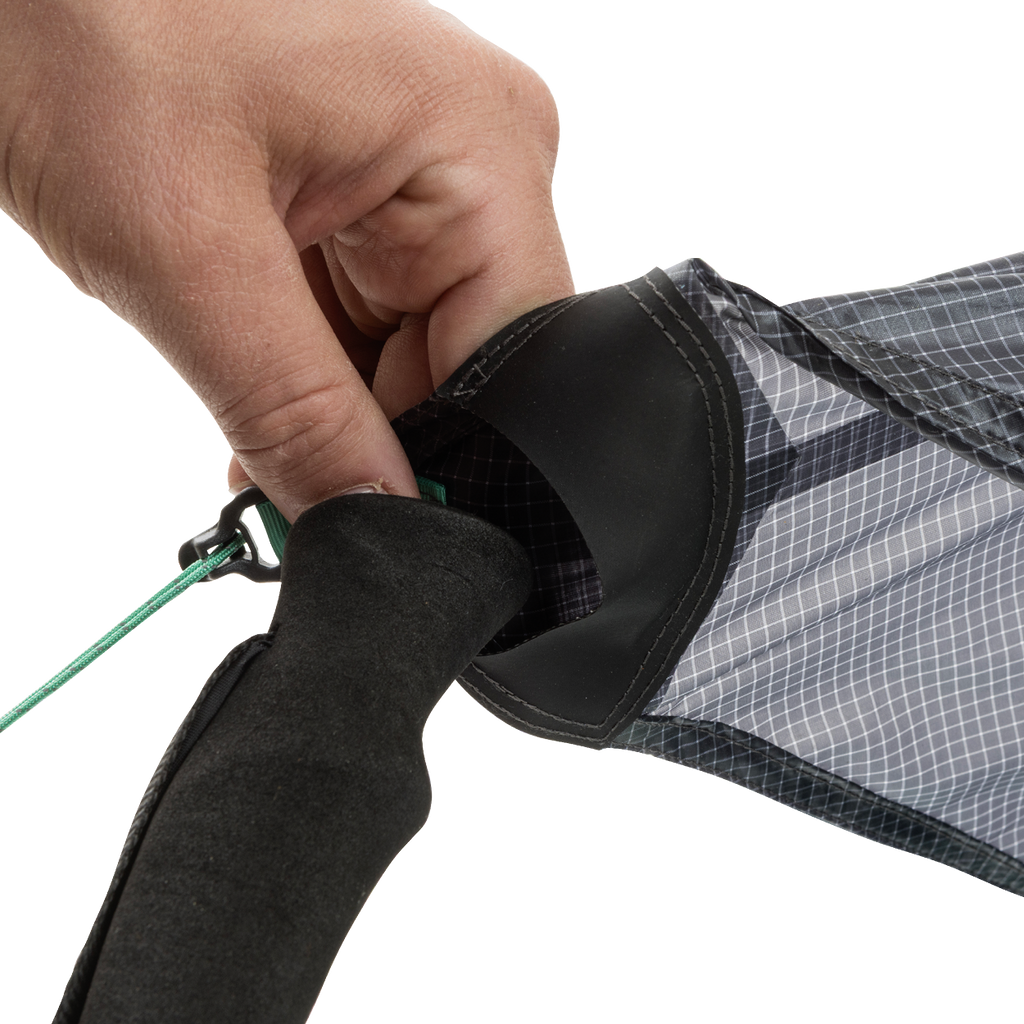 A close-up of a hand tying a green string to the end of the black and gray String Ridge VST 1.5 by Big Agnes, highlighting its detailed fabric and handle—ideal for assembling ultralight shelters or VST tents on your outdoor trips.
