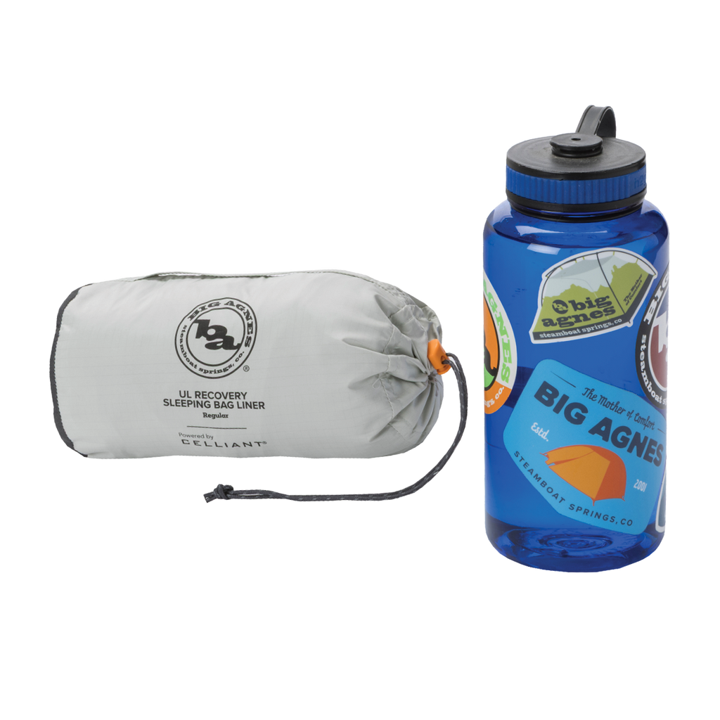 A compact gray Big Agnes Returns UL Recovery Sleeping Bag Liner in a stuff sack sits beside a blue water bottle decorated with colorful stickers.
