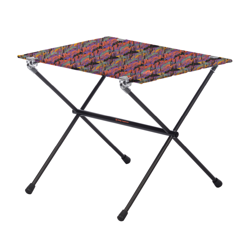 The Big Agnes Returns Woodchuck Camp Table - Alpenglow is a lightweight, foldable outdoor table featuring black metal legs and a rectangular top with a colorful abstract design, shown on a plain white background.