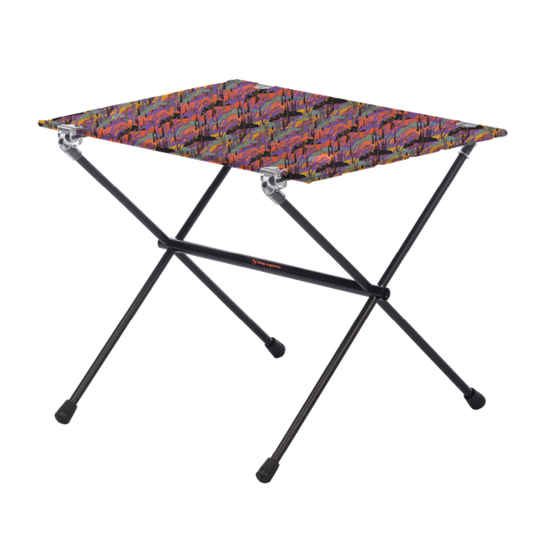 The Big Agnes Returns Woodchuck Camp Table - Alpenglow is a lightweight, foldable outdoor table featuring black metal legs and a rectangular top with a colorful abstract design, shown on a plain white background.