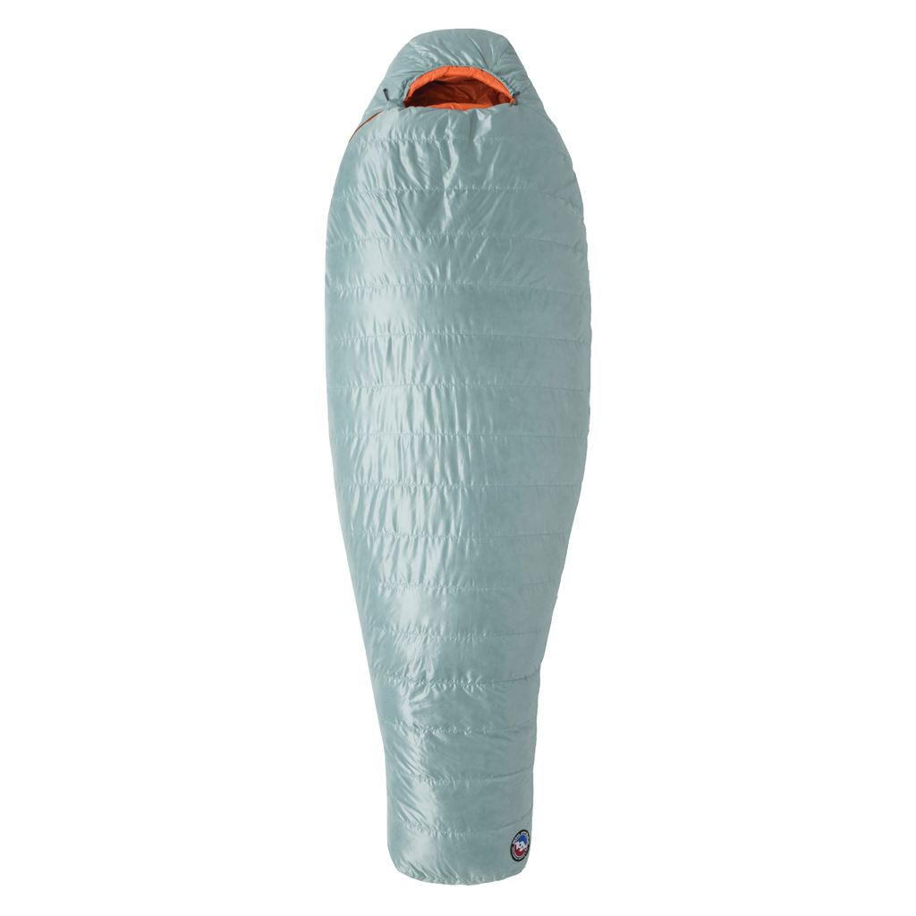 The Big Agnes Returns Women's Greystone 30° mummy sleeping bag in light blue features an orange interior, tapered footbox, and hooded top for head coverage. It is displayed upright against a plain white background.